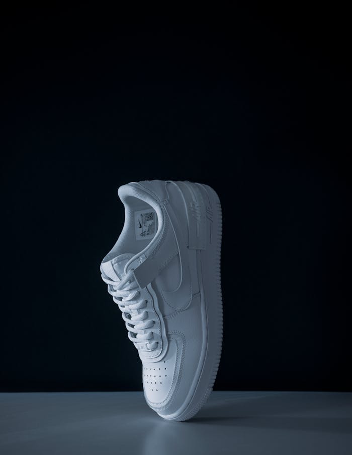 Elevated white sneaker on black background in a studio shoot for fashion and sports.